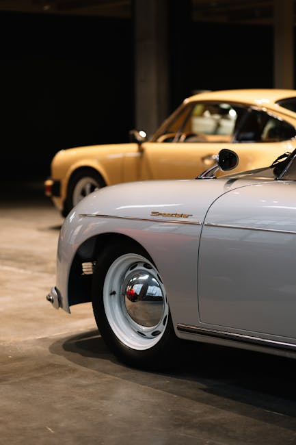 Classic beige and white sports cars showcased in an indoor garage setting.