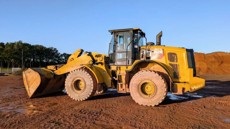 A large yellow wheel loader at a construction site under a blue sky.